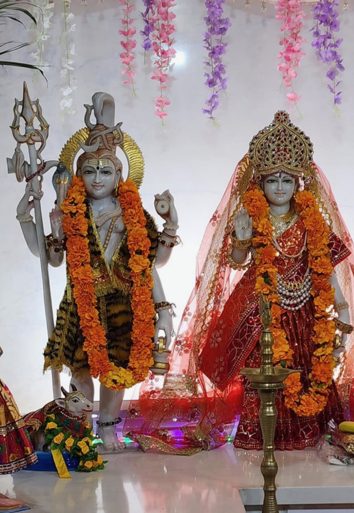 Bhagwan Shiv and Mata Parvati — the temple's own murtis, garlanded with marigolds